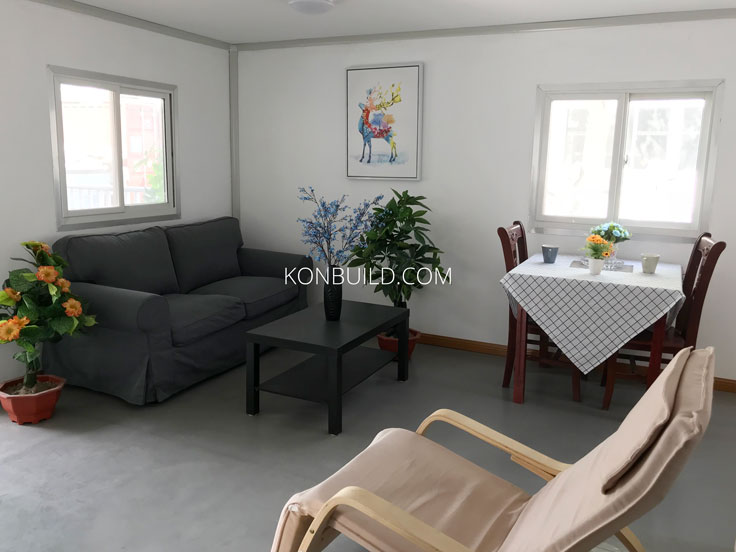 Living area in a container home with basic furniture.