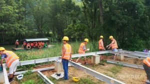 The base of the building is constructed on the pylons. Tourist are going down the river in the background.